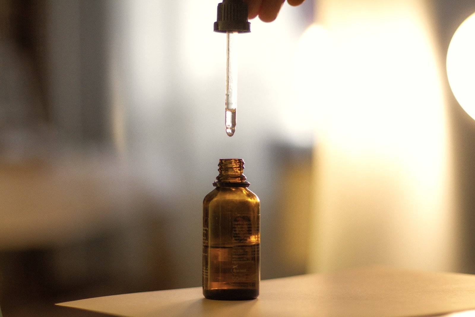 Sıcak ışıkta amber renkli şişeye serum damlatan bir damlalık